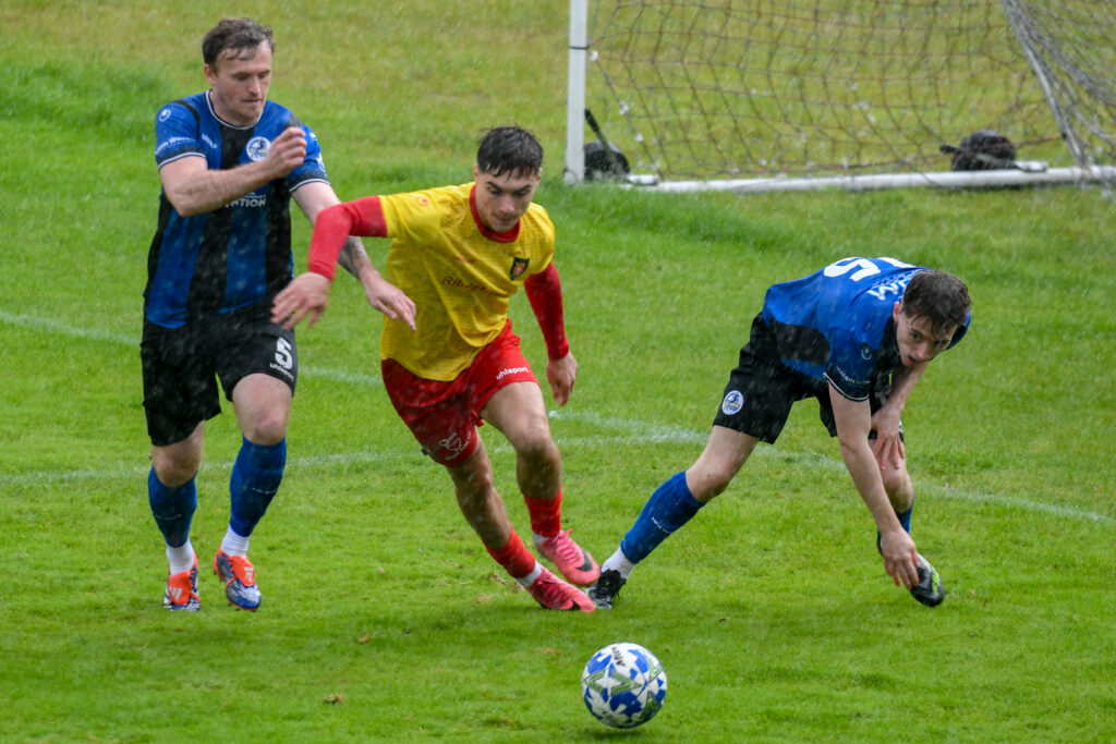 Albion Rovers' Alex McCaw battling two Cumbernauld Colts players. 